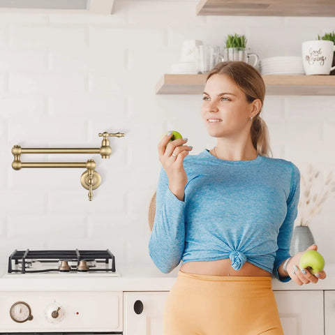 Woman in kitchen with Gold Pot Filler Faucet Wall Mount Copper Folding Faucet With Two Handles And Double Joint Swing Arms