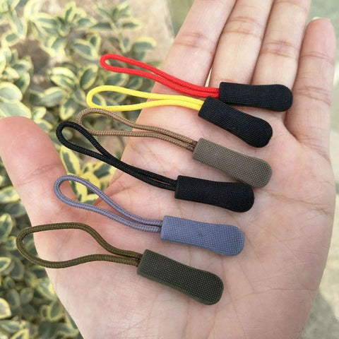 20 Pack Easy Grip Zipper Pulls With Cord For Backpacks And Jackets Non Slip Rubber Tab Replacement Slider Repair Kit For Bags, Tents, Clothes DIY Accessory Fix Red displayed in hand.