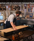 xTool P2 CO2 laser cutter in a workshop; a person loads a long plywood board into the machine