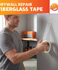 Man applying Pro Grade Drywall Repair Fiberglass Tape 2 Inch By 100 Foot Industrial Grade Extra Strength on wall crack