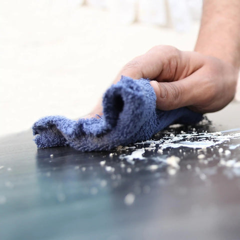Person using blue recycled color terry cloth for cleaning surface; close-up of hand and rag in action.