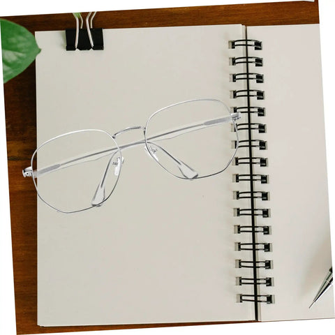Clear glasses frame resting on a spiral notebook, representing Sunglasses Repair Kit Quick Fix For Eyeglass Temples And Replacement Arms Spare Glasses Legs Durable DIY Repair Tools For A Secure Fit And Sleek Look.