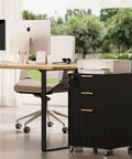 Slick Fluted 3 Drawer Rolling File Cabinet With Secure Lock, Heavy Duty Casters, Compact Printer Stand Table And Under Desk Wooden Storage Organizer For Home Office Workstation In Matte Black next to sleek desk and printer.