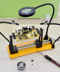 Helping Hands Magnetic Soldering Station with Pro Grade 360 Degree Flip, two flexible gooseneck arms, 3X magnifying glass over PCB