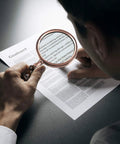 Person using Old School 10X Magnifying Glass With Wooden Handle And Copper Frame, Real Glass Lens for reading detailed print on paper.