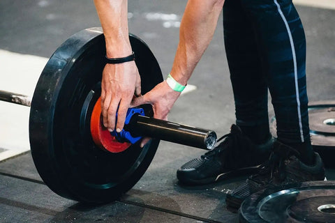 Athlete using Heavy Duty 2 Inch Barbell Clamps Quick Release Pair Locking Olympic Weight Plate Collars Red And Black Easy Weight Swaps For Powerlifting Home Gym Fitness Training Clips on a barbell during a gym session.