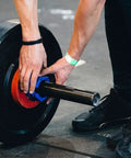 Heavy Duty 2 Inch Barbell Clamps Set Quick Release Locking Collars For Olympic Weight Plates in use on gym floor.