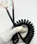 Close-up of Top Shelf Expandable Coiled Power Cord Spring Retractable Extension Wire, 5 core black cable in hand.