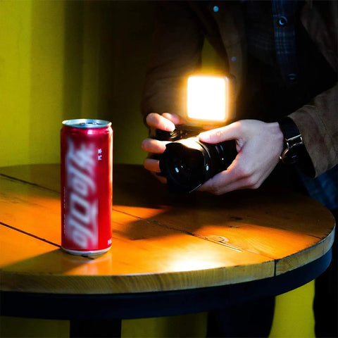 Person using VL49 RGB Video Light For Cameras Pro Grade 360 Full Color LED Panel to illuminate a can on a table