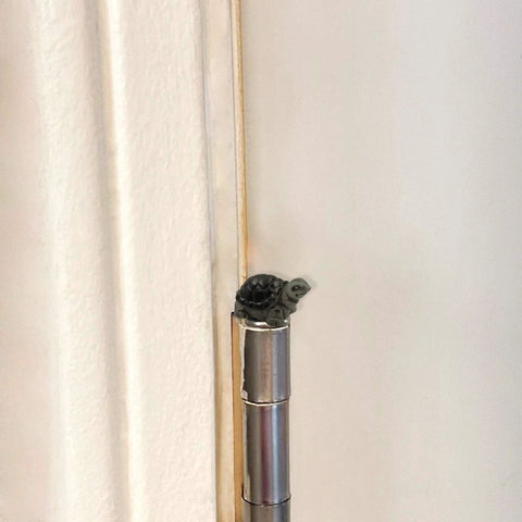 Tiny magnetic turtle head ornament on door hinge, part of the Cute Tortoise Hinge Heads Decorative Topper Set Of Six For Doors And Metal Surfaces.