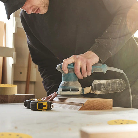 Woodworker using 5 Inch 220 Grit Hook And Loop Sanding Discs 8 Hole Dustless Random Orbit Sandpaper for finishing on wooden surface