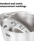 Close-up of stainless steel angled jigger with dual ounce and tablespoon markings, showing easy reading from above design.
