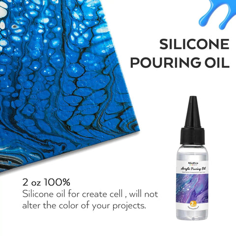 Close-up of acrylic pour art with silicone pouring oil bottle, blue and white patterns visible.