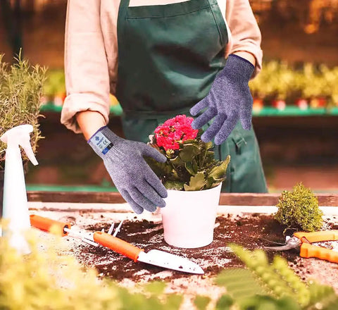 Gardener wearing Pro Chef Cut Resistant Kitchen Gloves EN388 Level 5, tending to a potted plant with gardening tools visible.