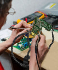 Man using Helping Hands Soldering Station With Flexible Y Shaped Arms And Non Slip Desk Clamp Base for electronics repair.