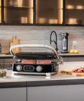 SMEG MGF01 Retro Countertop Electric Grill and Panini Press With Swappable Plates For Waffles, Burgers, And Steak in stylish kitchen setting.