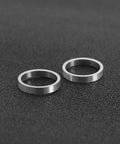 Two silver aluminum alloy bicycle chainring bolt spacers washers lying flat on black surface, 2mm thick, 10mm inner diameter.