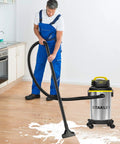 Person using Heavy Duty Wet And Dry Vacuum Cleaner with 4 Gallon Tank and 4 HP Power, stainless steel canister in a kitchen.