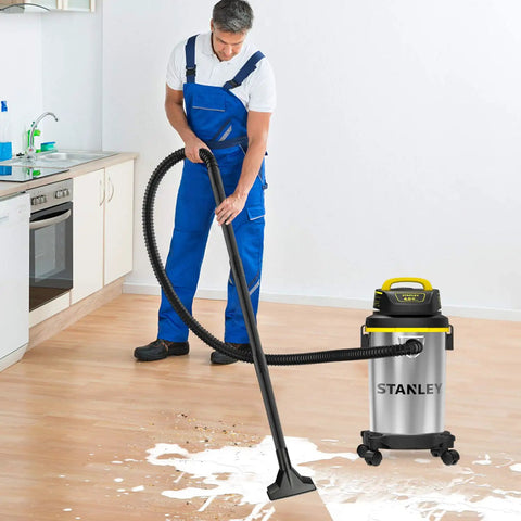 Person using Heavy Duty Wet And Dry Vacuum Cleaner with 4 Gallon Tank and 4 HP Power, stainless steel canister in a kitchen.