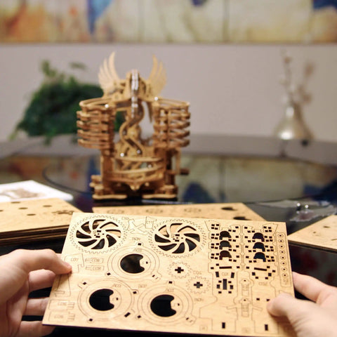 Hands holding parts of Wooden Marble Run Dragon Kit Hands On 3D Mechanical Model With Marble Track and 15 Steel Balls.