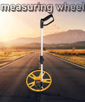 Badafaci Rolling Measuring Wheel, Foldable Handle on a road, featuring a durable yellow wheel and ergonomic black grip.