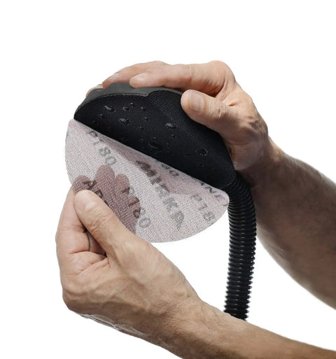Hands attaching 6 inch mesh disc to Dust Free Roundy Hand Sanding Block Kit with 13 ft vacuum hose for cleaner sanding.