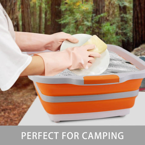 Person washing a dish in a Large Collapsible BBQ Prep Tub With Lid 4.22 Gal 16L Foldable Camping Sink at a forest campsite.