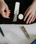 Two Pack Of Killer Heavy Duty Crewel Hand Sewing Needles With Super Easy Self Threading Eyes And A Hella Handy Storage Box on table with scissors.