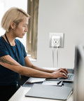 4 In 1 European Travel Plug Adapter With US Outlet And USB Ports on wall socket while woman works on laptop