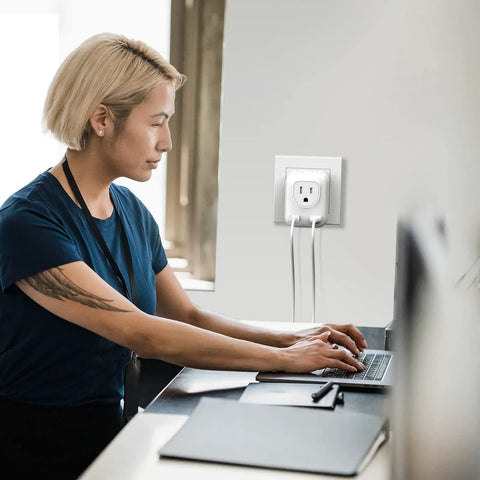 4 In 1 European Travel Plug Adapter With US Outlet And USB Ports on wall socket while woman works on laptop