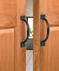 4 Inch Black Iron Cabinet Pulls Pack Of 2 With Ergonomic Grip installed on wooden doors, showcasing the vintage rustic style and matte black finish.