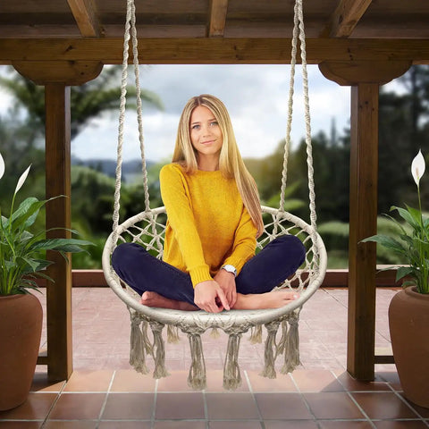 Woman sitting on Boho Macrame Swing Chair For Indoor And Outdoor Use, Durable Cotton Hanging Hammock with tassels, patio view.