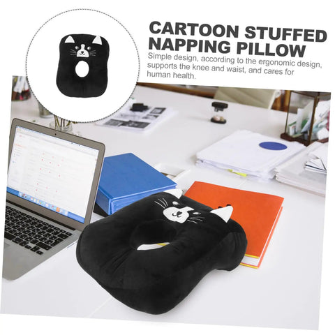 Black cartoon cat office desk nap pillow for easy naps on white desk with laptop and books around.