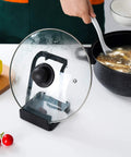 Hella Convenient Multi Function Kitchen Utensil And Pot Lid Organizer Pad With Spoon Rest Ladle Holder Catch Mat Drip Tray Washable Heavy Duty Stick Mount Black, showing glass lid rack with pot.