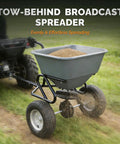 110 Lb Tow Behind Fertilizer Broadcast Spreader With 10 Adjustable Drop Rate And 11.4 Inch Tire in use on grass terrain