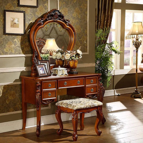 Elegant vintage-style dressing table set with a carved mirror and cushioned stool, featuring ornate wood detailing, placed in a classic room.
