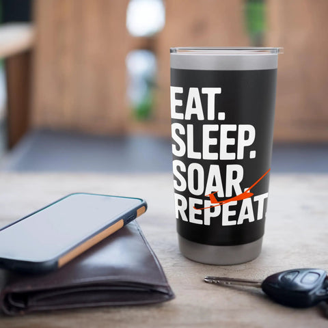 Black tumbler with 'Eat. Sleep. Soar. Repeat' text, on a table next to a phone and keys. Glider Pilot Stainless Steel Insulated Tumbler Keeps Coffee Hot Or Ice Cold For Sailplane Fans, Flight Crew, And Flight School Students On Ridge Soaring, Tow Launches, And Club Flights.