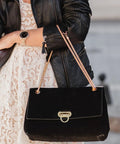 Handbag front view: black velvet with gold-tone turn-lock clasp and chain strap