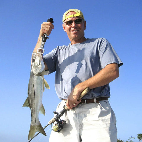 Angler using Pro Grade Fish Lip Gripper Pliers With Upgraded 4.3 Inch EVA Foam Handle for holding catch against blue sky