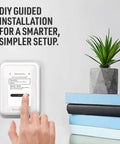 WiFi Smart Thermostat With Touchscreen Display shown during DIY installation guide, adjacent to books and plant