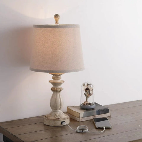 Farmhouse Style Table Lamp with USB Charging Port, white washed rustic finish, 22 inch with tapered drum shade, on a wooden table
