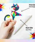 Hand holding dark fabric heat transfer paper showing print side and back side with colorful cat design for inkjet and laser printers.