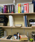 Books and items on wood shelves supported by Heavy Duty 12-Inch By 8-Inch Shelf Brackets With 600 Lb Capacity 10 Pack White Metal L Supports.