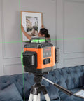 100ft Green Self Leveling Laser Level With 3 X 360 Degree Cross Lines on tripod, used for picture alignment in a room.