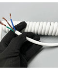 Real Deal White Retractable Spiral Power Cord Featuring Heavy Duty Telescopic Spring Design That Snaps Back Up To Fifteen Meters Plus Works Like A Charm Inside Shops, showing exposed copper wires.