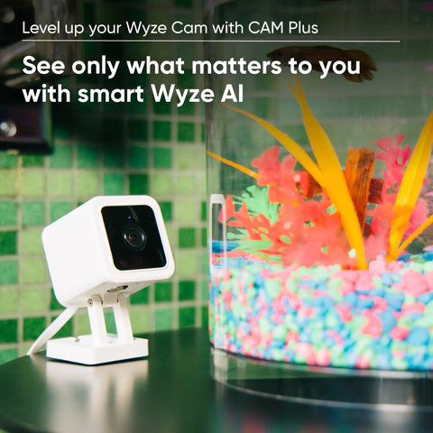 Indoor And Outdoor Plug In Smart Security Camera With AI Motion Alerts near a vibrant fish tank setup indoors.