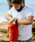 Person holding storage bag for Mantis Ultralight Hammock With Mosquito Net And Storage Bag For All Seasons in Ember Orange