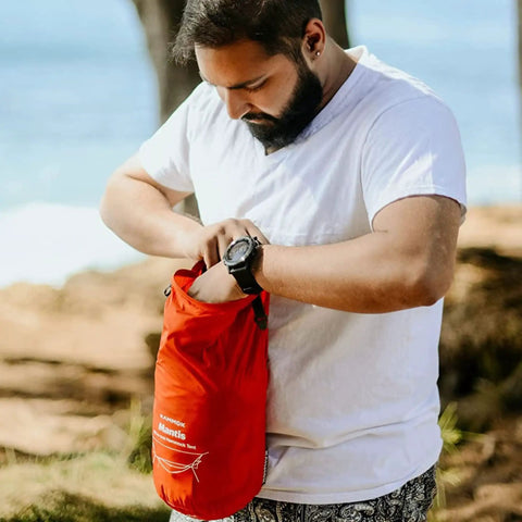 Person holding storage bag for Mantis Ultralight Hammock With Mosquito Net And Storage Bag For All Seasons in Ember Orange