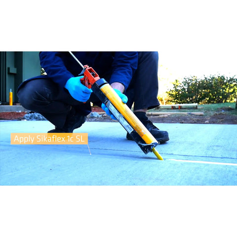 Worker applying Sikaflex 1C SL Self Leveling Polyurethane Sealant for limestone and concrete expansion joints on a sidewalk.