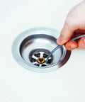 Hand Crank Drain Auger with quarter inch cable being inserted into sink drain, showing light duty plumber snake use.